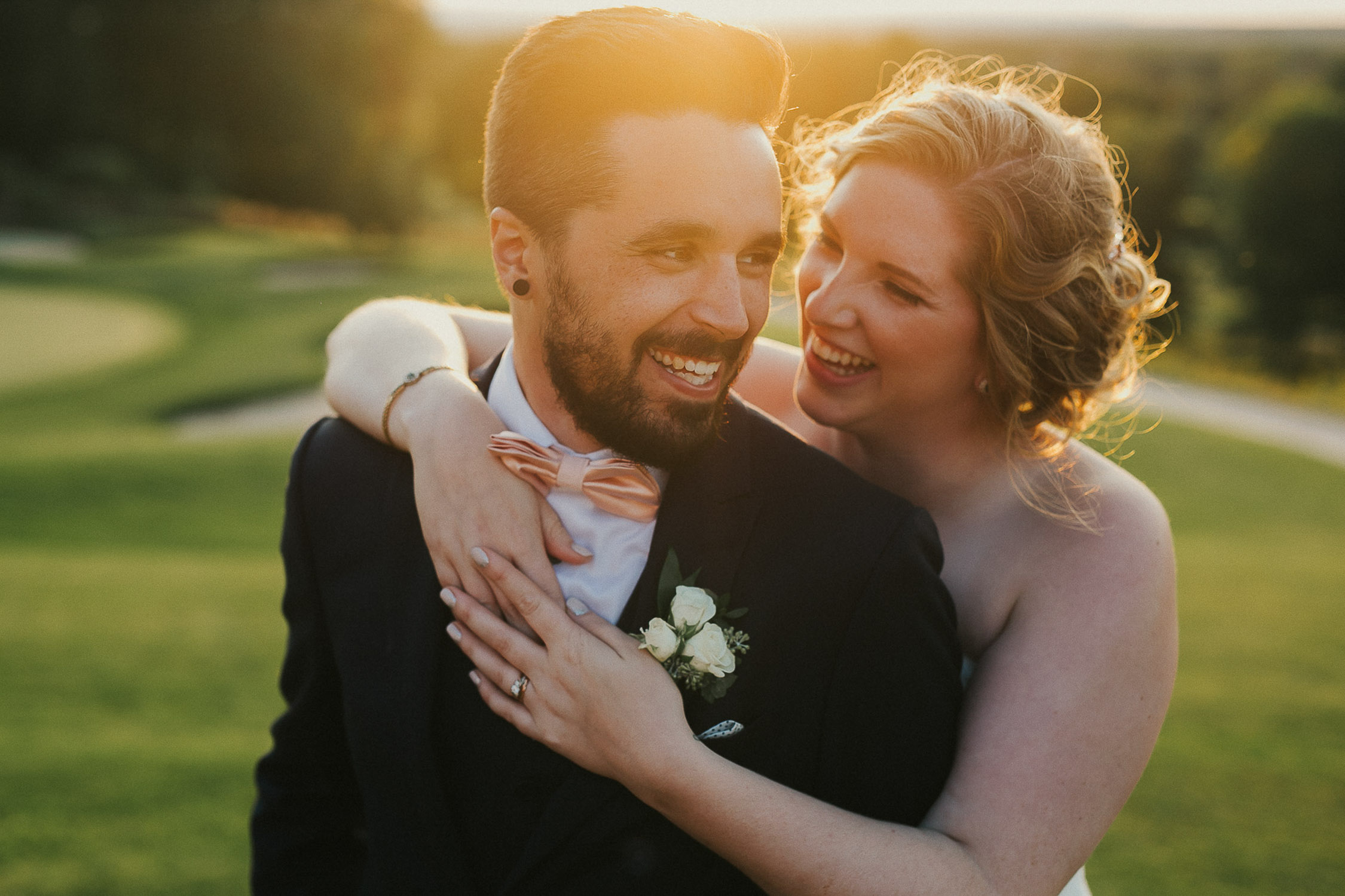 Happy couple hug on golf course with raving reviews for Michael Steingard Photography.